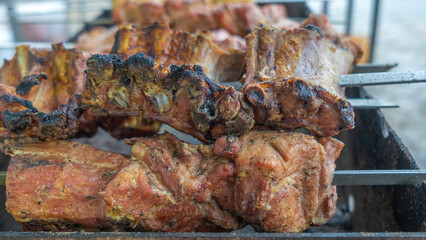 Tasty food roasting on skewers. Delicious bbq kebab grilling on open grill. Outdoor kitchen. Food festival in city.