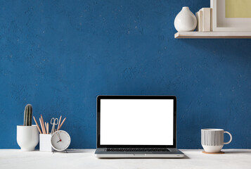 Laptop with blue wall and white table mock up.	
