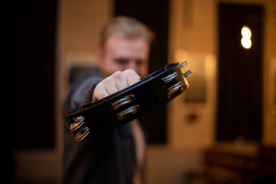 A young guy with a beard plays the tambourine - Powered by Adobe