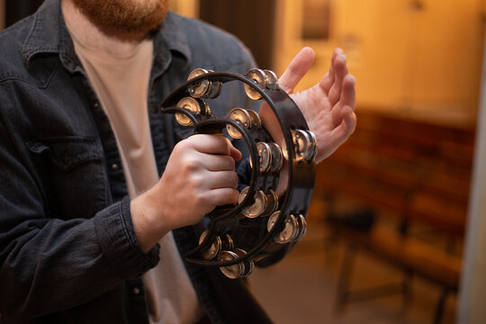 A young guy with a beard plays the tambourine