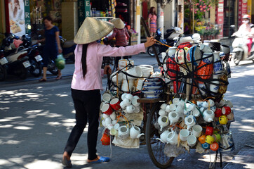 A woman carrying hundreds of kitchen utensils by bicycle on street, Hanoi, Vietnam 

