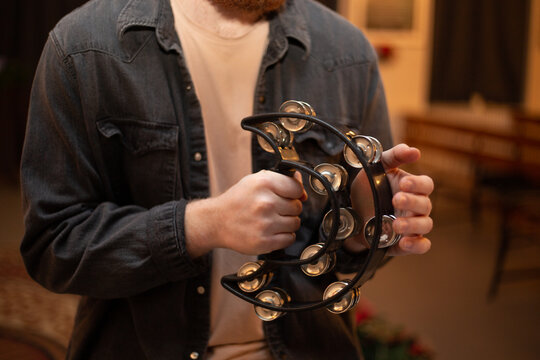 A young guy with a beard plays the tambourine