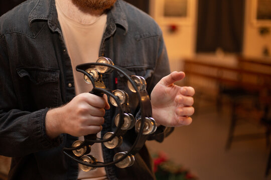 A young guy with a beard plays the tambourine