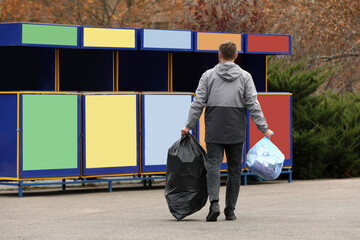 Man with garbage at recycling point outdoors, back view