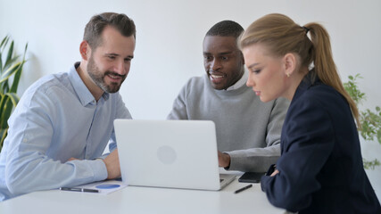 Fototapeta premium Cheerful Business People Celebrating Success while using Laptop in Office