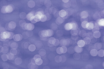 Beautiful festive background from the bokeh effect from glare in the form of circles in the tones color of the year 2022, Very Peri