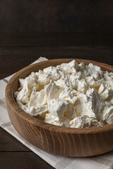 Cottage curd cheese in a bowl on old wooden table.