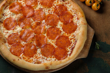 Pizza with salami on a wooden background. Cherry tomatoes.