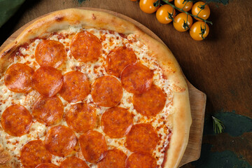 Pizza with salami on a wooden background. Cherry tomatoes.