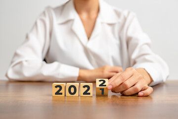 Happy New Year 2022, Female hands flipping wooden blocks to turn 2021 into 2022.