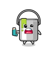 paint tin mascot having asthma while holding the inhaler