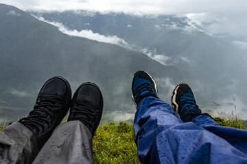 young couple hiker feet at the mountain top with dramatic sky at morning from flat angle