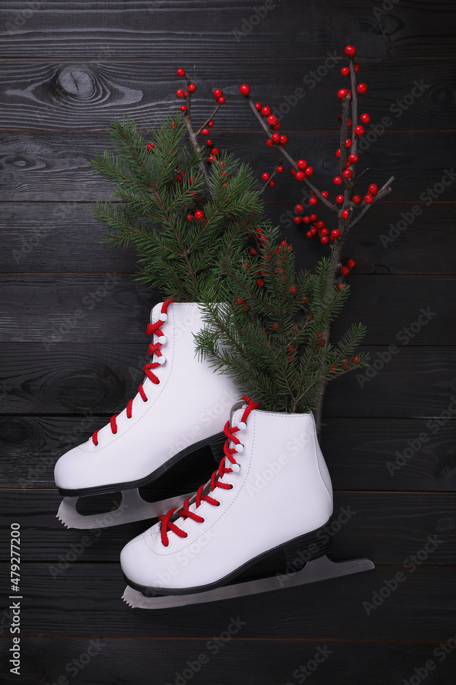 Wall mural Pair of ice skates with Christmas decor on black wooden background, flat lay