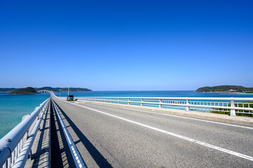 Car crossing Tsunoshima Ohashi Bridge over the emerald green sea