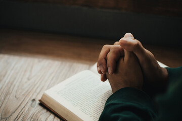 Man hands clasped together on Holy Bible in church concept for faith, spirituality, and religion,...