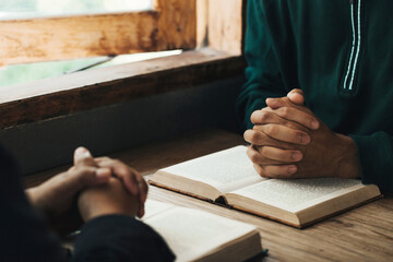 Handsome man hands are praying for God's blessings on an open bible with window light Pray in the Morning. Power of hope or love and devotion.