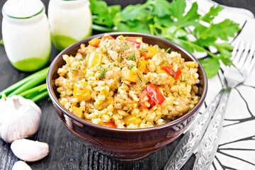 Barley porridge with minced meat in bowl on dark board