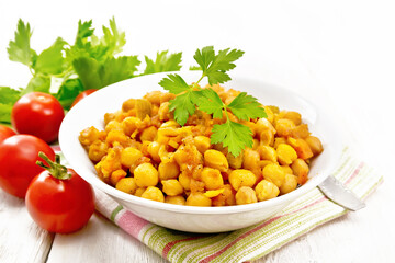 Chickpeas stewed with vegetables in plate on wooden board