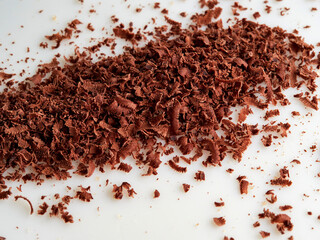 Dark chocolate pieces isolated on white background. Chocolate bar chunks, shavings and cocoa crumbs Top view.