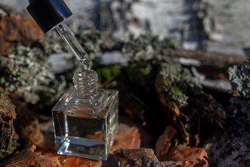 Bottle with dropper with oil on pillow of birch bark. Blurred background. Selective focus. Front...