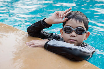 Asian happy kid playing slider in swimming pool