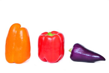 three colorful paprika fruits - red, yellow and purple isolated on a white background