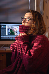 A woman looks through the blinds at the early morning sunlight.