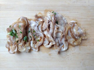 Grilled black pork, thinly sliced, garnished with spring onions in a wooden plate
