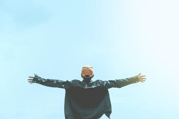 Copy space of man rising hands on blue sky white clouds abstract background. Freedom feel good and...
