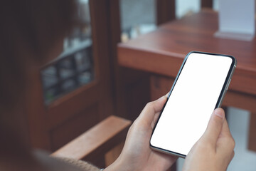 Cell phone mockup image blank white screen.  Woman hand holding, using mobile phone at coffee shop.