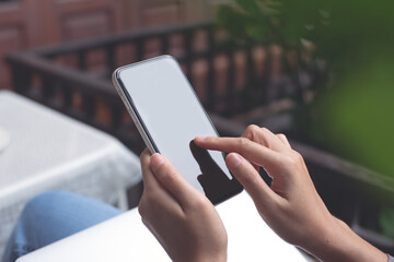 Cell phone mockup image blank white screen.  Woman hand holding, using mobile phone at home.