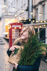 Young woman with a Christmas tree and a gift box on a blurred background.