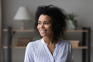 Happy dreamy beautiful curly motivated young african american multiracial woman looking in...