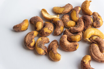 Close up of roasted cashew nuts with skin on white background. Cashew nuts salted with peel- rich in protein, antioxidants, and fiber.