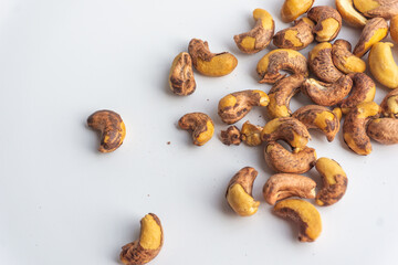 Close up of roasted cashew nuts with skin on white background. Cashew nuts salted with peel- rich in protein, antioxidants, and fiber.
