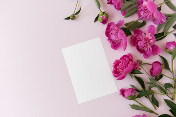 Fototapeta premium Blank branding paper card sheet with mockup copy space and elegant peonies flowers on pink background. Aesthetic flowers composition