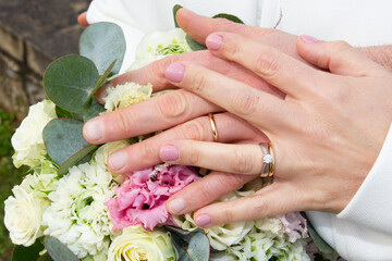 Obraz na płótnie Canvas bride and groom hands wedding fingers rings close up on bouquet flowers marriage