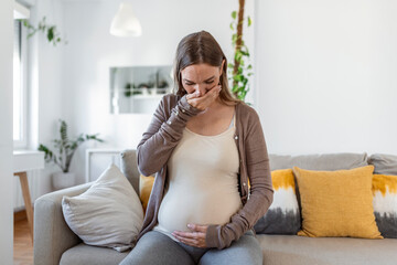 young pregnant woman suffering from toxicosis at home. maternity lady having morning sickness...