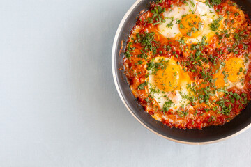 Shakshuka in a pan. Middle eastern traditional dish. Fried eggs with tomatoes, pepper, vegetables and herbs. 