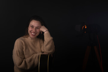 Young woman posing with an acoustic guitar with smoke and black background