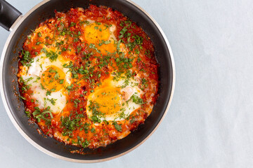 Tasty and Healthy Shakshuka in a Frying Pan. Eggs Poached in Spicy Tomato Pepper Sauce.