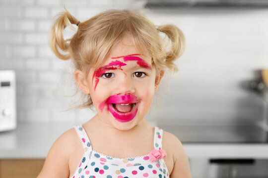 Funny toddler with lipstick all over her face smiling at camera