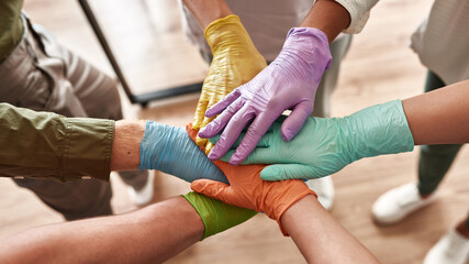 People in medical gloves stack hands on each other