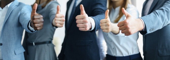 Cropped shot of a group of businesspeople standing in office showing thumb up