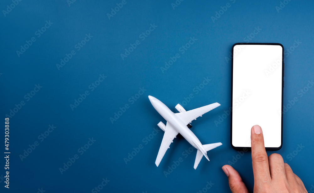 Poster white empty screen on smartphone with touching finger and airplane model toy on blue background with