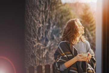 Happy cheerful beautiful curly young woman enjoying morning coffee and nature view on the terrace...