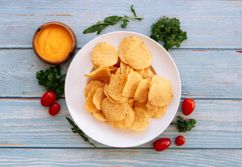 Crispy Nacho With Spicy Cheese dip in a white plate. Traditional fast food on wooden background top view