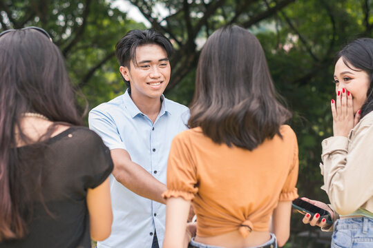 A young man introduces himself to a lady and her excited friends. Dating concept among young adults.