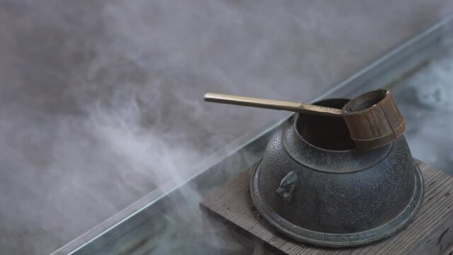 Gardening Japanese style inspiration from tea ceremony, bamboo dipper with old kettle chagama with smoke floating around
