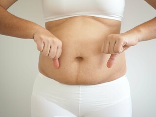 Asian fat woman has overweight. she shows excess fat of the abdomen on white background. closeup photo, blurred.